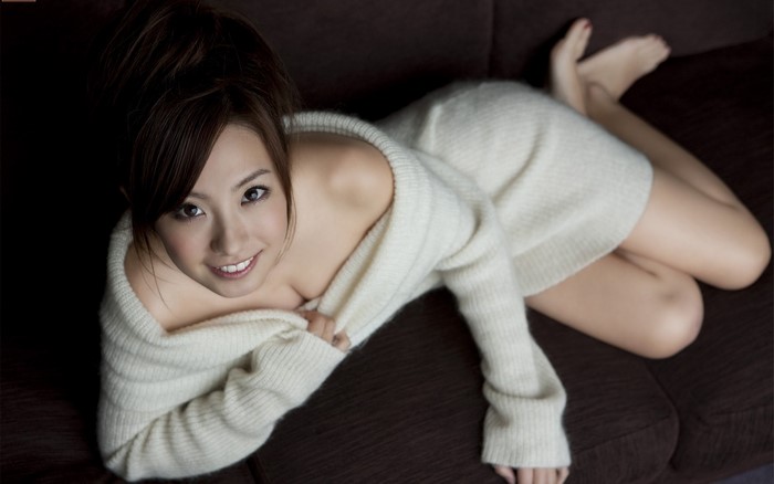 Japanese woman in white sweater lying on couch