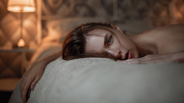 Woman with blue eyes lying on a bed