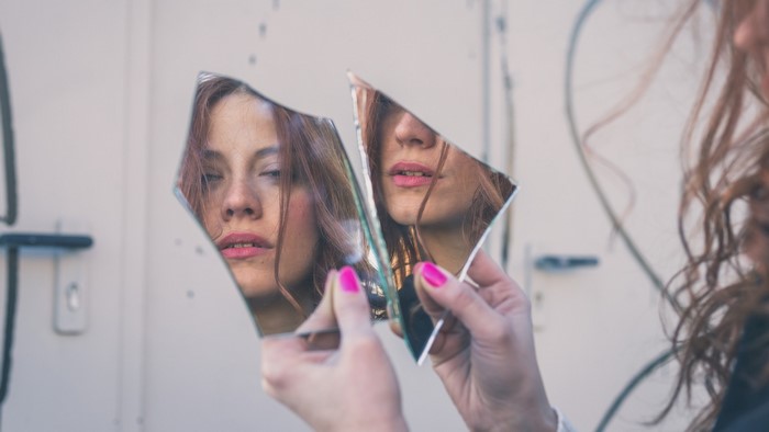 Woman holding broken mirror reflecting her face