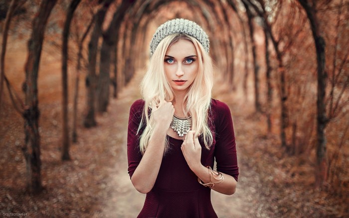 Woman with blonde hair and blue eyes wearing a hat and dress