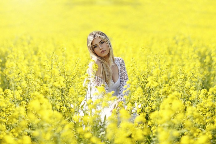 Woman in white dress in a field of yellow flowers