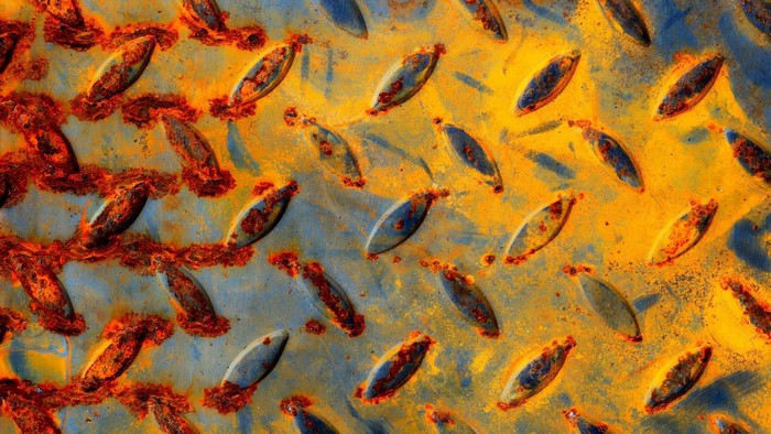 Rusted diamond plate metal texture with yellow and blue paint