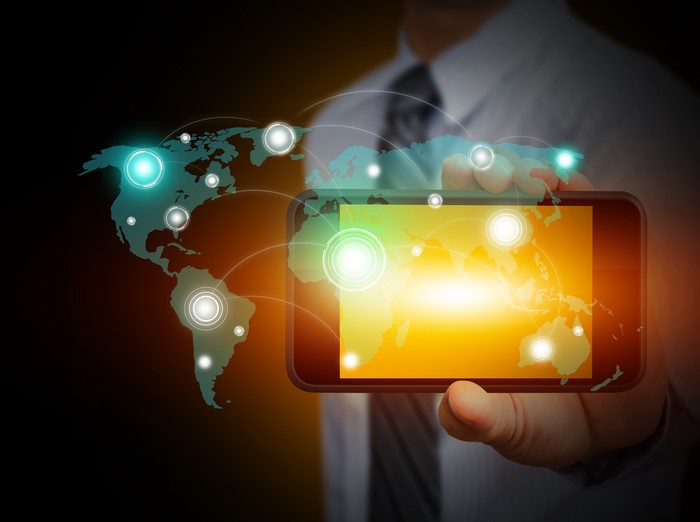 Man holding smartphone with digital world map overlay
