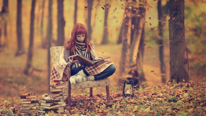 Redhead reading books in autumn forest
