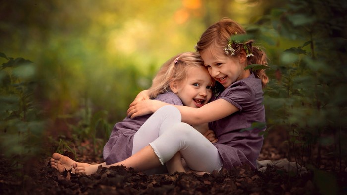 Two young girls hugging in a forest