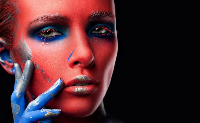 Model with red and blue face paint and green eyes