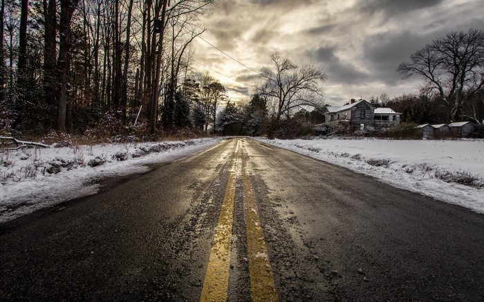 Snowy road leading to an abandoned house in winter
