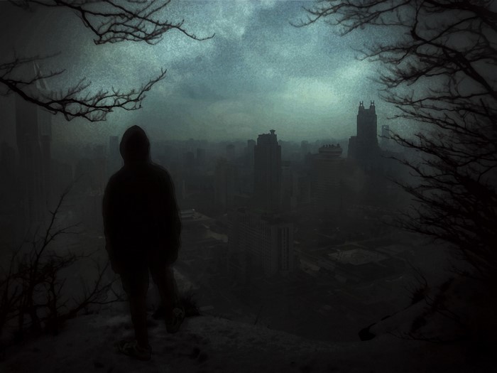 Person in hoodie overlooking a dark, foggy city at night