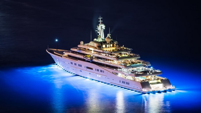 Luxury yacht illuminated at night with blue underwater lights