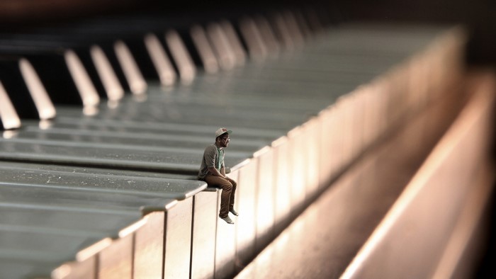 Man sitting on piano keys, surreal photo manipulation