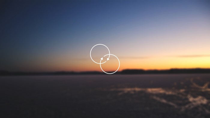 Two interlocking circles with arrows on a blurred sunset background