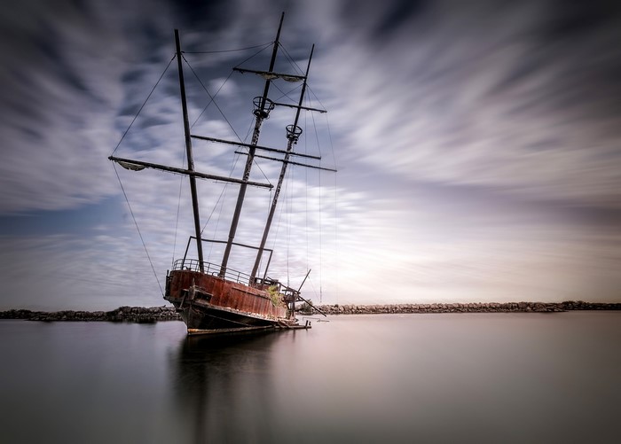 Abandoned ship on the water with streaky clouds