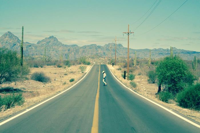 Person skateboarding on a desert road with mountains