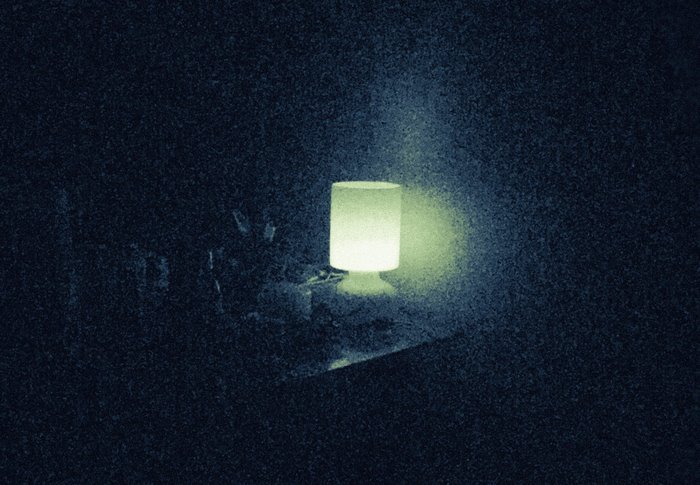 A glowing lamp in a dark room with film grain