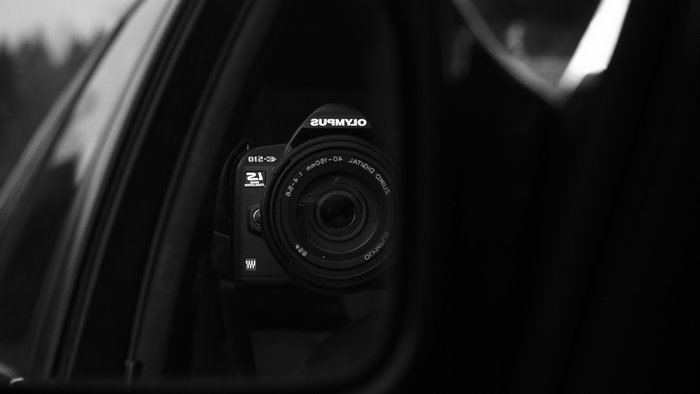 Olympus camera reflected in a car's side mirror