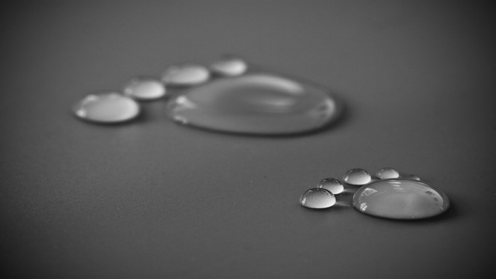 Water droplets forming footprints on a dark surface