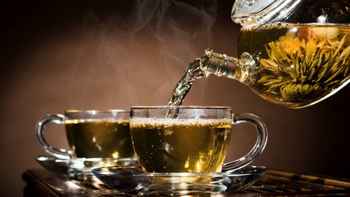 Tea being poured from a teapot into cups