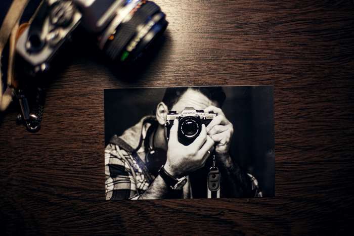 Man taking a selfie with an Olympus OM-10 analog camera