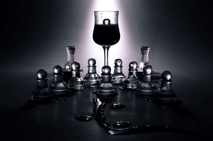 Glass chess pieces arranged around a wine glass