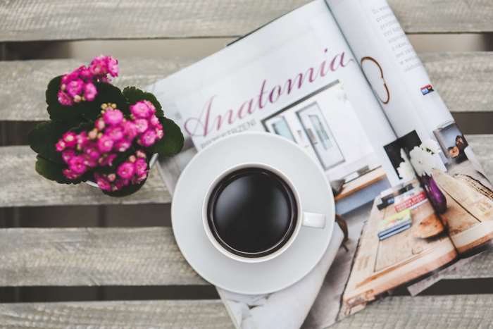 Cup of coffee on a magazine with pink flowers