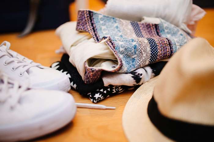 Stack of clothes with shoes and hat for travel