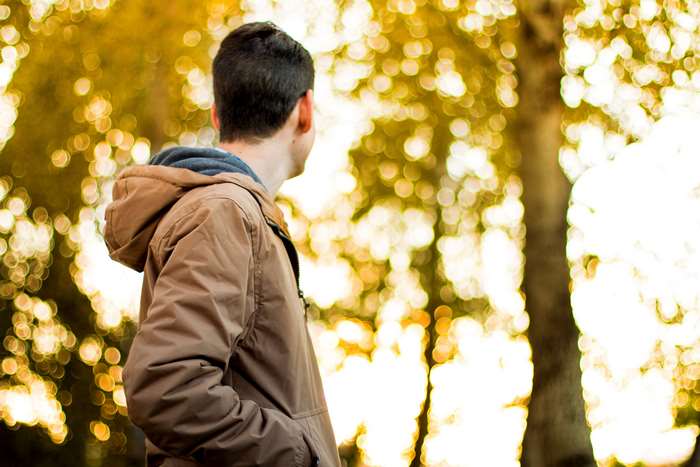 Man in brown jacket in autumn park with bokeh