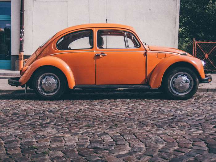 Orange Volkswagen Beetle on cobblestone street