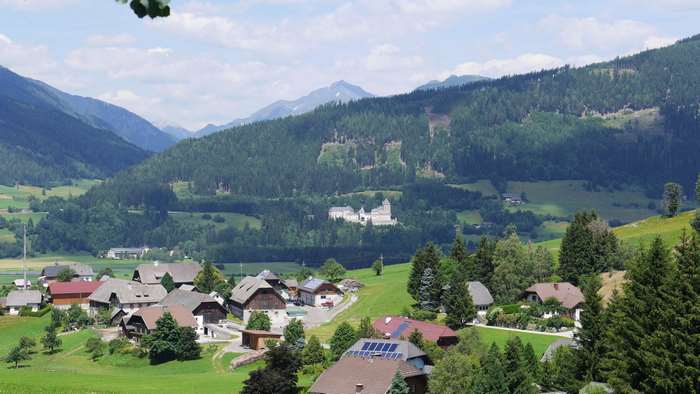 Castle in a mountain valley with houses and forest