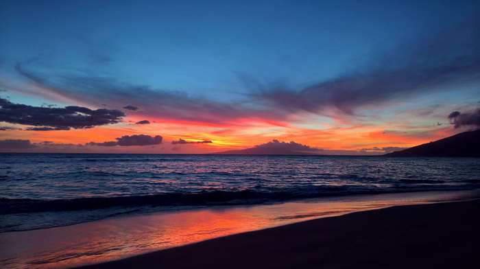Sunset over the ocean with colorful clouds and reflection