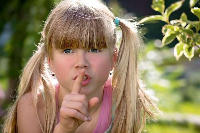 Girl with pigtails making a shushing gesture