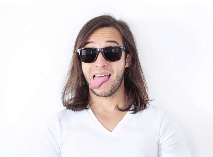 Man with long hair and sunglasses sticking out tongue