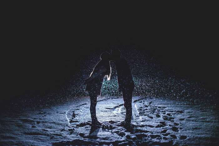 Couple kissing in the snow at night