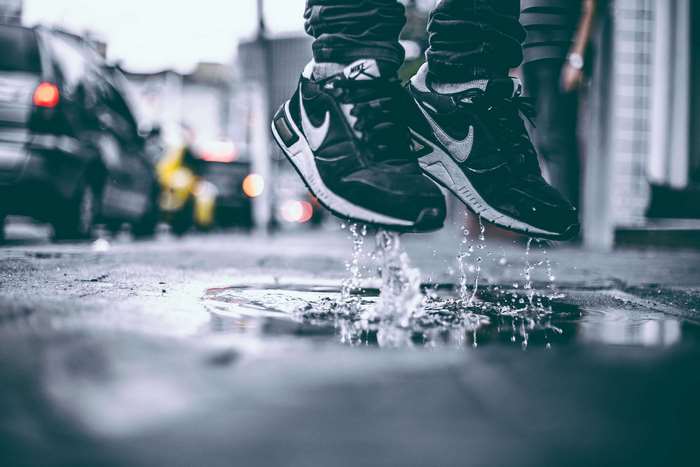 Person jumping in a puddle wearing Nike sneakers