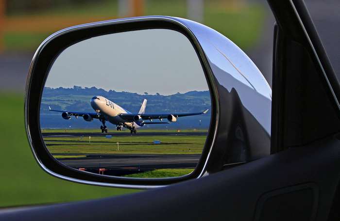 Airplane taking off reflected in a car's side mirror