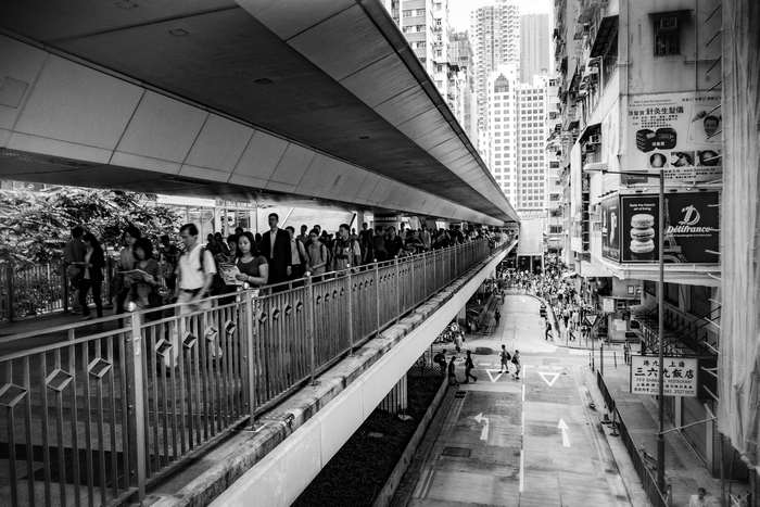 People walking on a footbridge in a busy city street