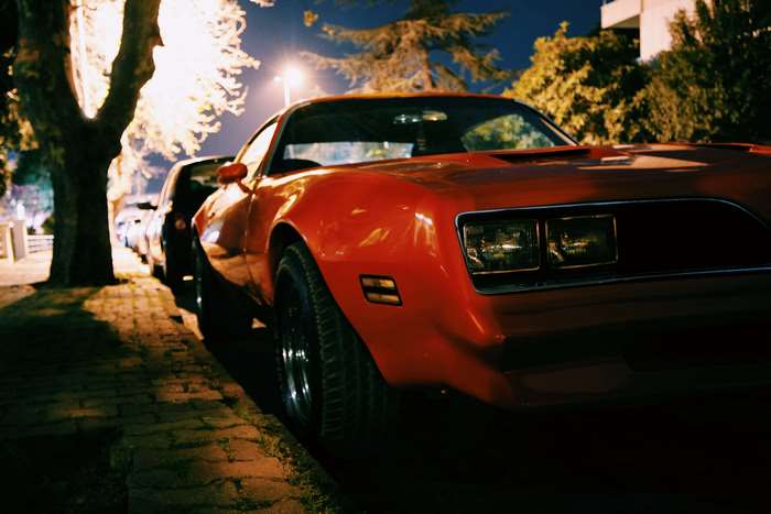 Red vintage muscle car parked at night