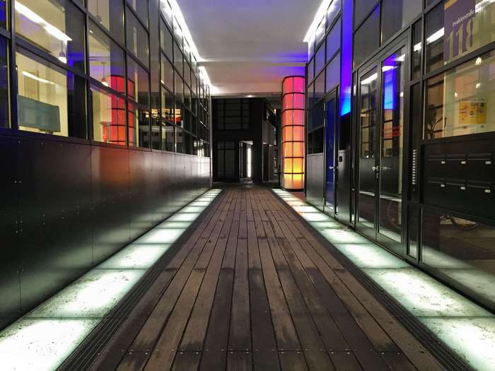 Modern glass corridor with wooden floor and colorful lights