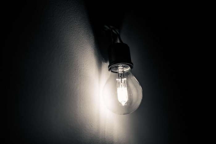 Hanging light bulb casting shadows on a wall