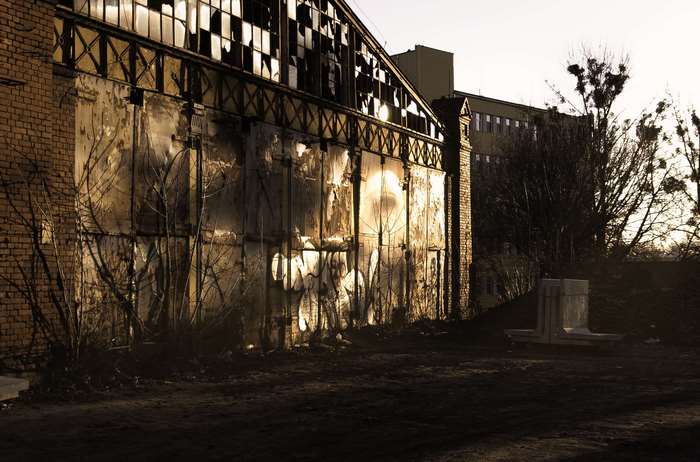 Abandoned industrial building with broken windows at sunset