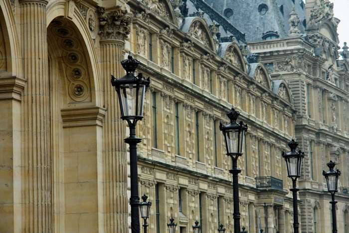 Street lamps in front of the Louvre Museum facade in Paris
