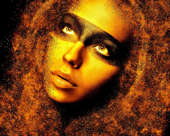 Woman's face with golden makeup and exploding particles