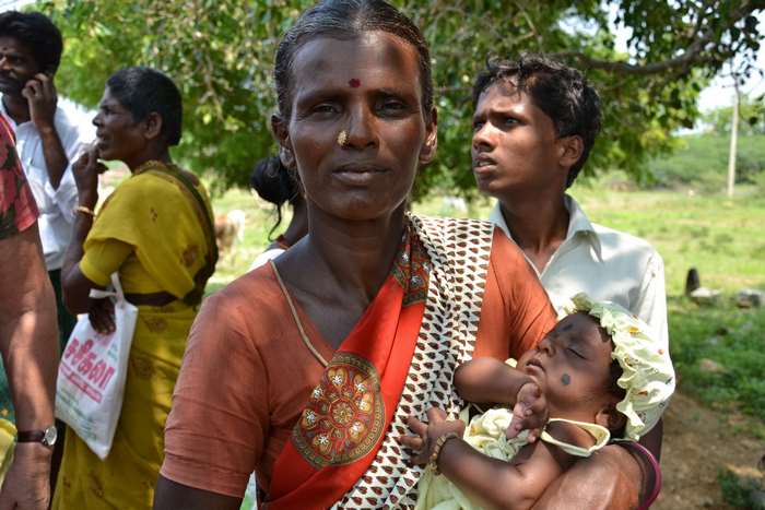 Indian woman holding a baby with people in the background