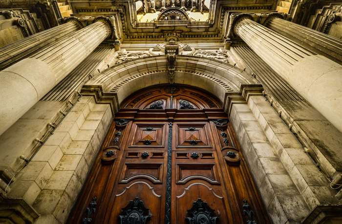 Grand wooden doors with ornate carvings and stone columns