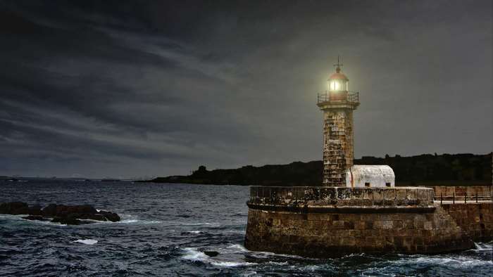 Lighthouse on a stone pier in stormy seas