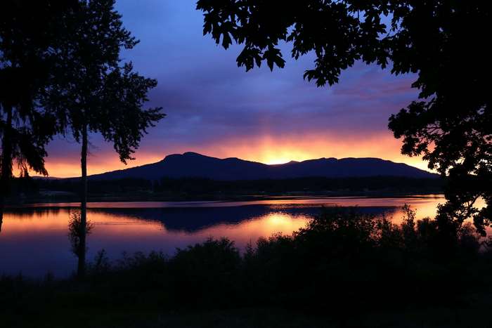 Sunset over a lake with mountains and trees