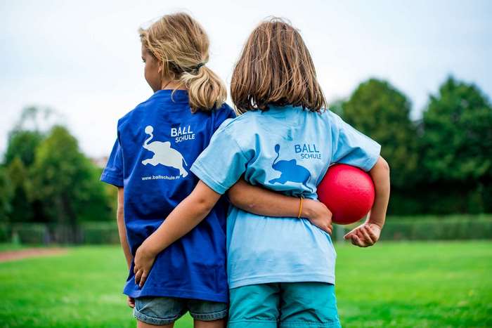 Two girls in sports shirts with elephant logo on grass