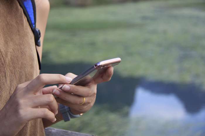 Woman texting on a smartphone near water