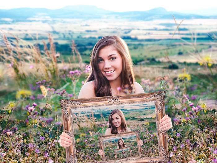 Young woman holding a frame with nested frames in a field