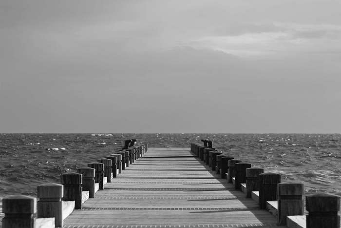 Wooden pier extending into the ocean under a cloudy sky
