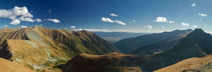 Panoramic view of mountains in autumn under a blue sky with clouds